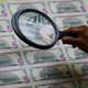 An employee examines a sheet of $5 bills as it comes off the printing machine at the U.S. Treasury’s Bureau of Engraving and Printing in Washington, DC July 20, 2018